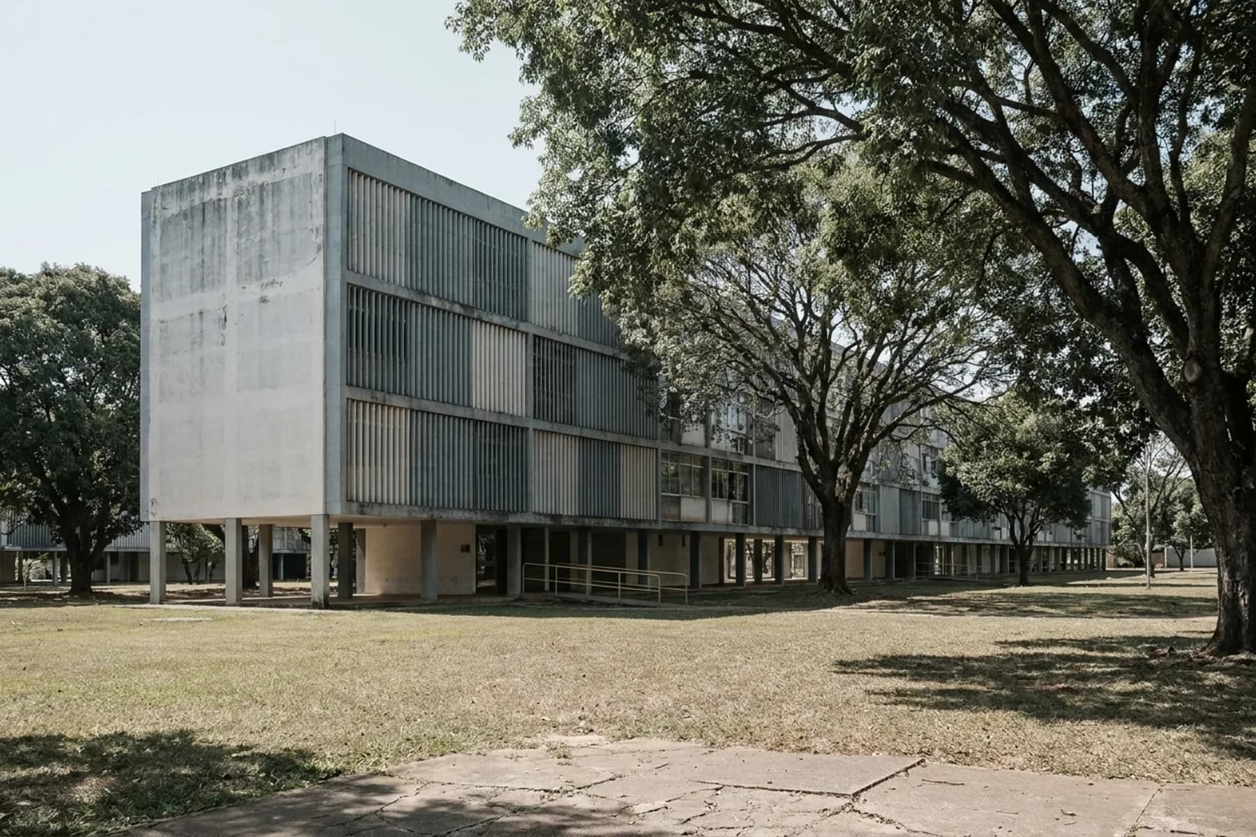 Bloco residencial modernista sobre pilotis, com brise de concreto e árvores ao redor, no estilo das superquadras de Brasília